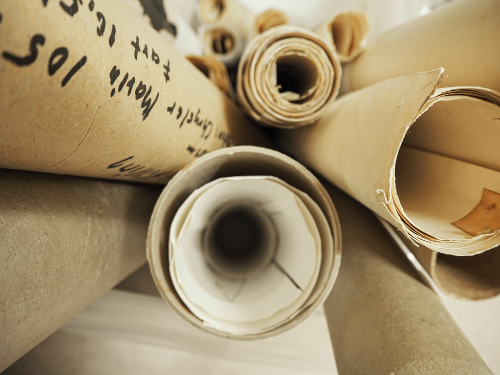 Several rolls of paper, some with text and sketches, are stacked and viewed from above at close range - perhaps planning the next program for the family.